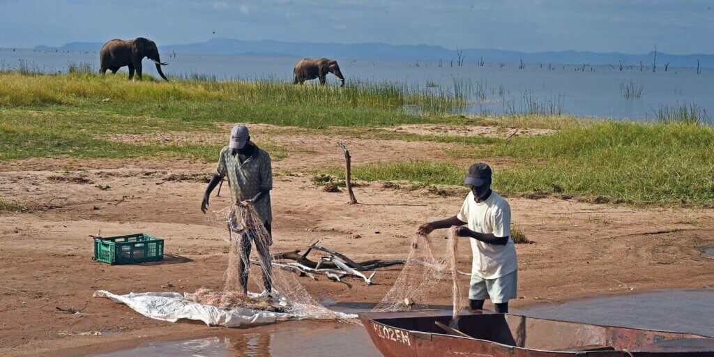Fisherman repairing nets at King's fishing village in Binga